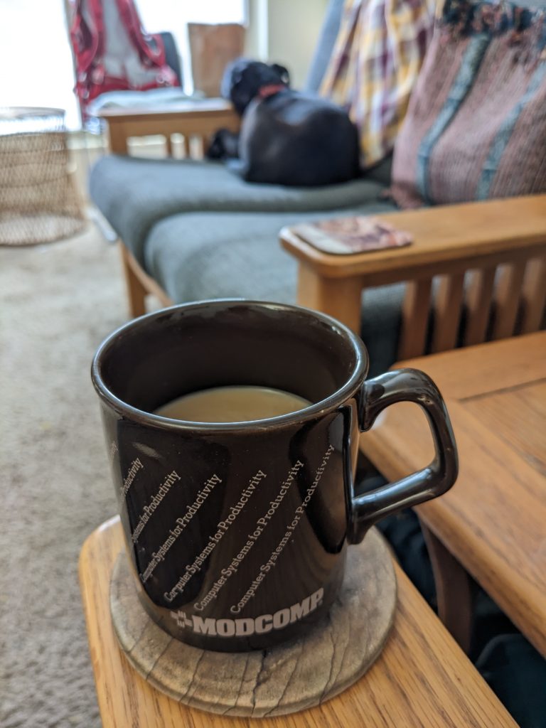 Photo of a brown Modcomp mug with a dog out of focus in the background.