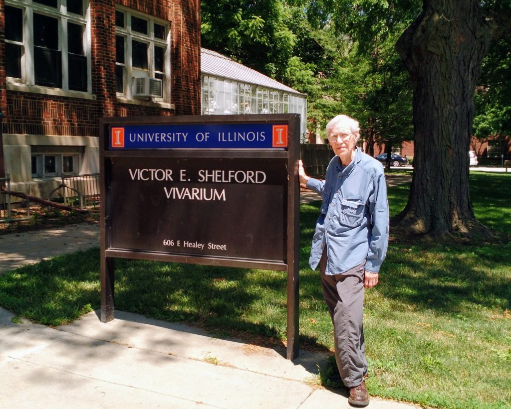 Richard Brewer standing next to the Victor E. Shelford Vivarium sign