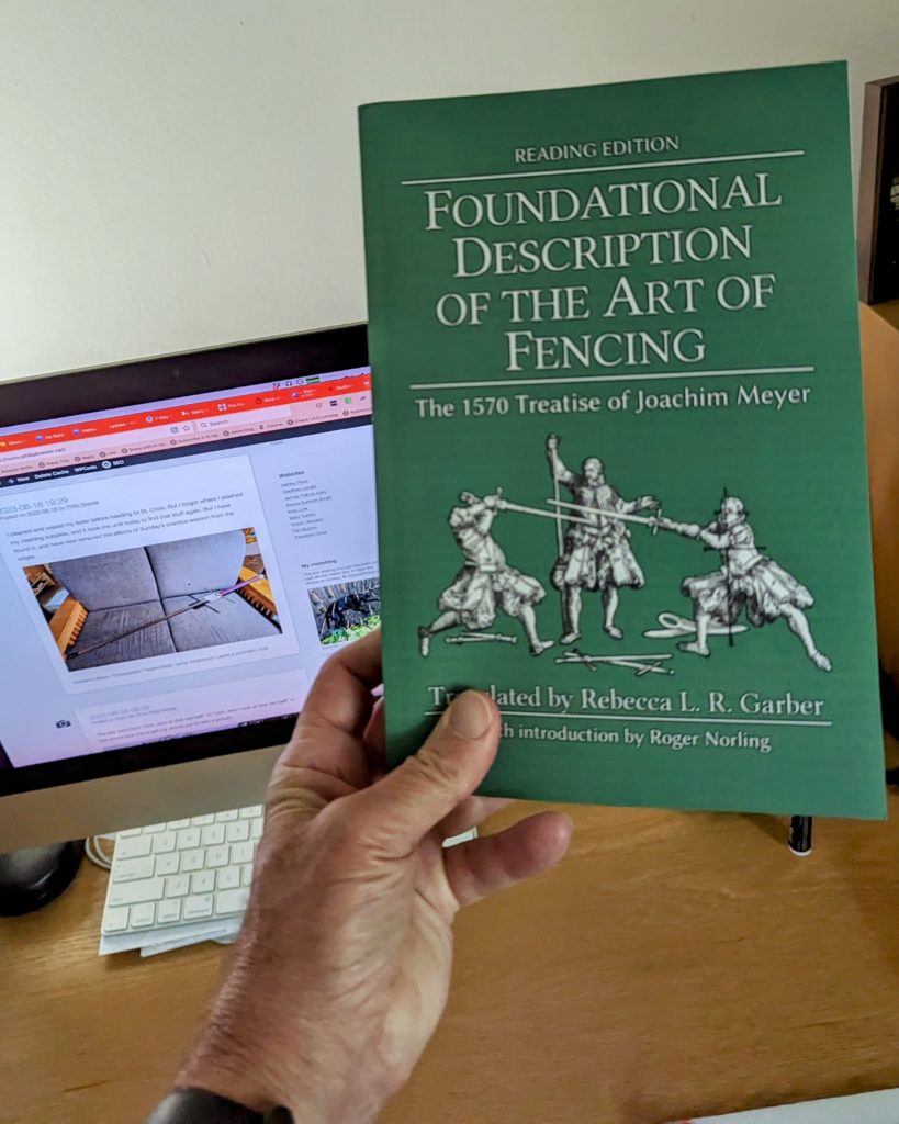 Copy of the new Rebecca L. R. Garber translation of Meyer's _Foundational Description of the Art of Fencing_, held in my hand in front of my computer