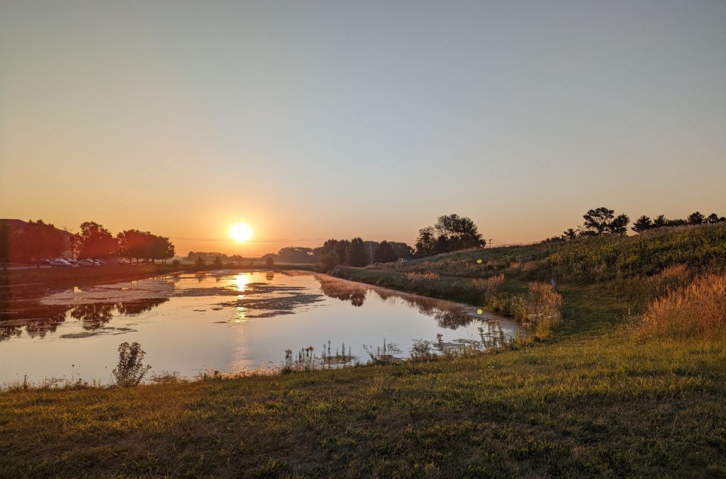 Sun over the detention pond by the prairie