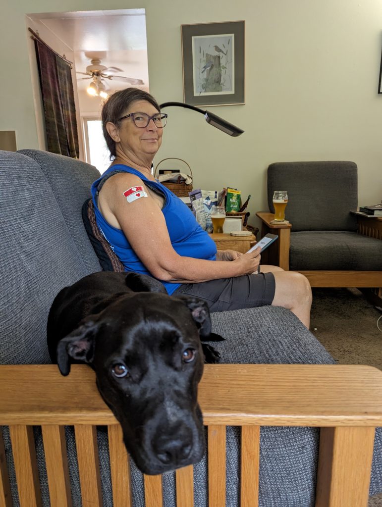 Ashley sprawled along the loveseat, with Jackie beyond her, showing us the two band-aids she got for two vaccinations.