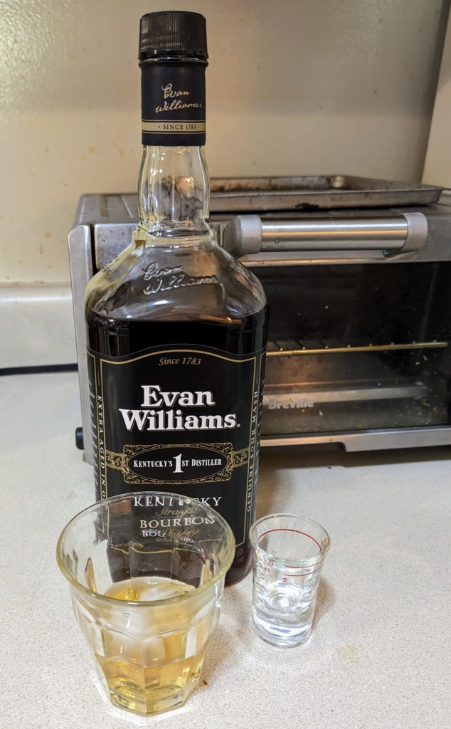 Evan Williams whiskey bottle with a modest pour into a glass, and a 2 cl shot glass