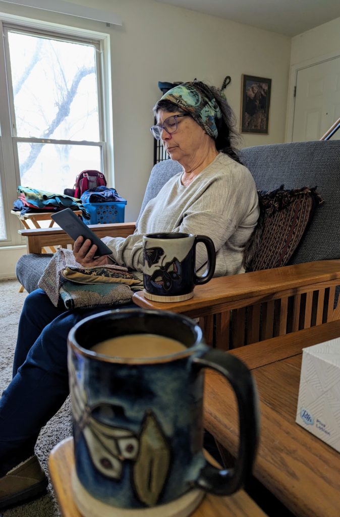 Photo of ackie reading, with my and Jackie's coffee mugs, in the foreground