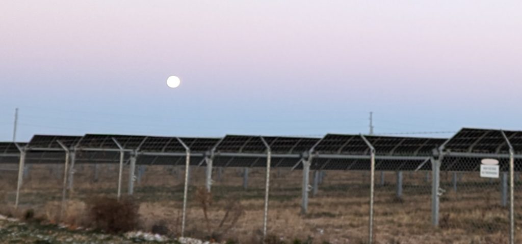 A large solar array pointed west toward the setting moon, taken just a few minutes before sunrise