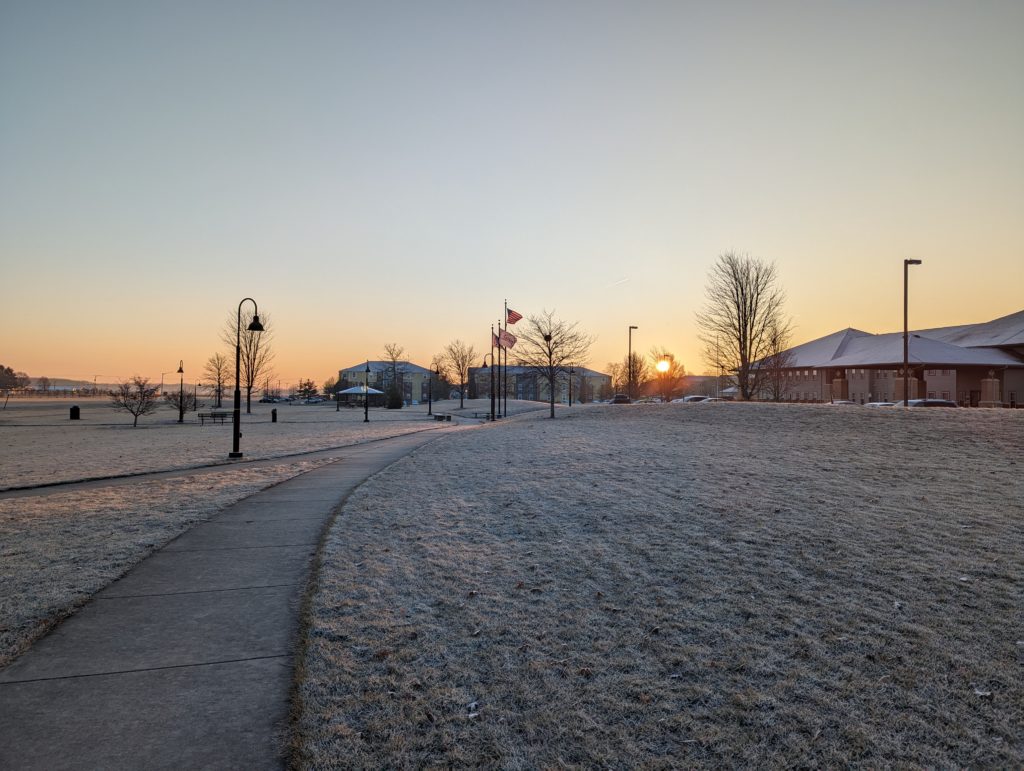 The sun rising between buildings, as seen from Dohme Park