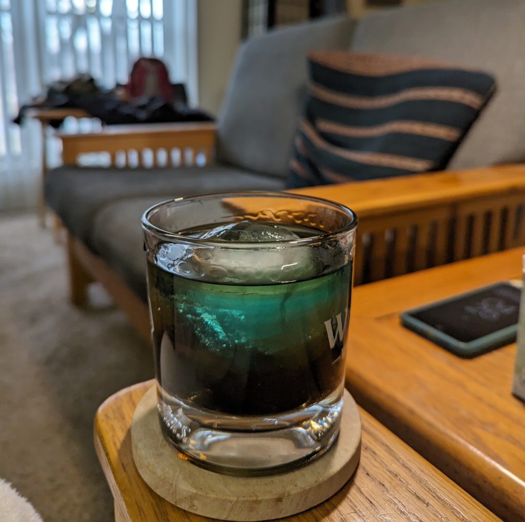Cocktail in a glass on a coaster with an ice sphere