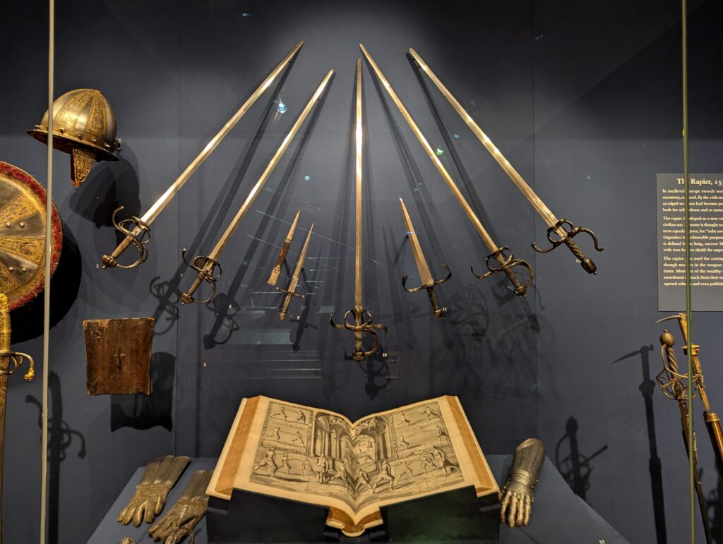 Display case with rapiers and a copy of Thibault's Academie de l’Espée