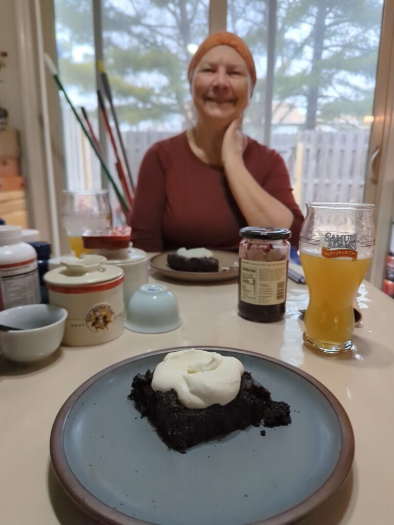 In the foreground a serving of flourless chocolate cake and across the table a woman with the same dish.